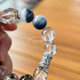 This beaded bracelet is crafted from a mesmerizing combination of Green Phantom Quartz, Blue Rabbit Hair Quartz, Hawk's Eye, Black Aurora Super Seven, and Herkimer. All the beads are natural crystals. The natural patterns of the crystals intertwine beautifully with the metallic accents, creating a unique and enchanting piece.