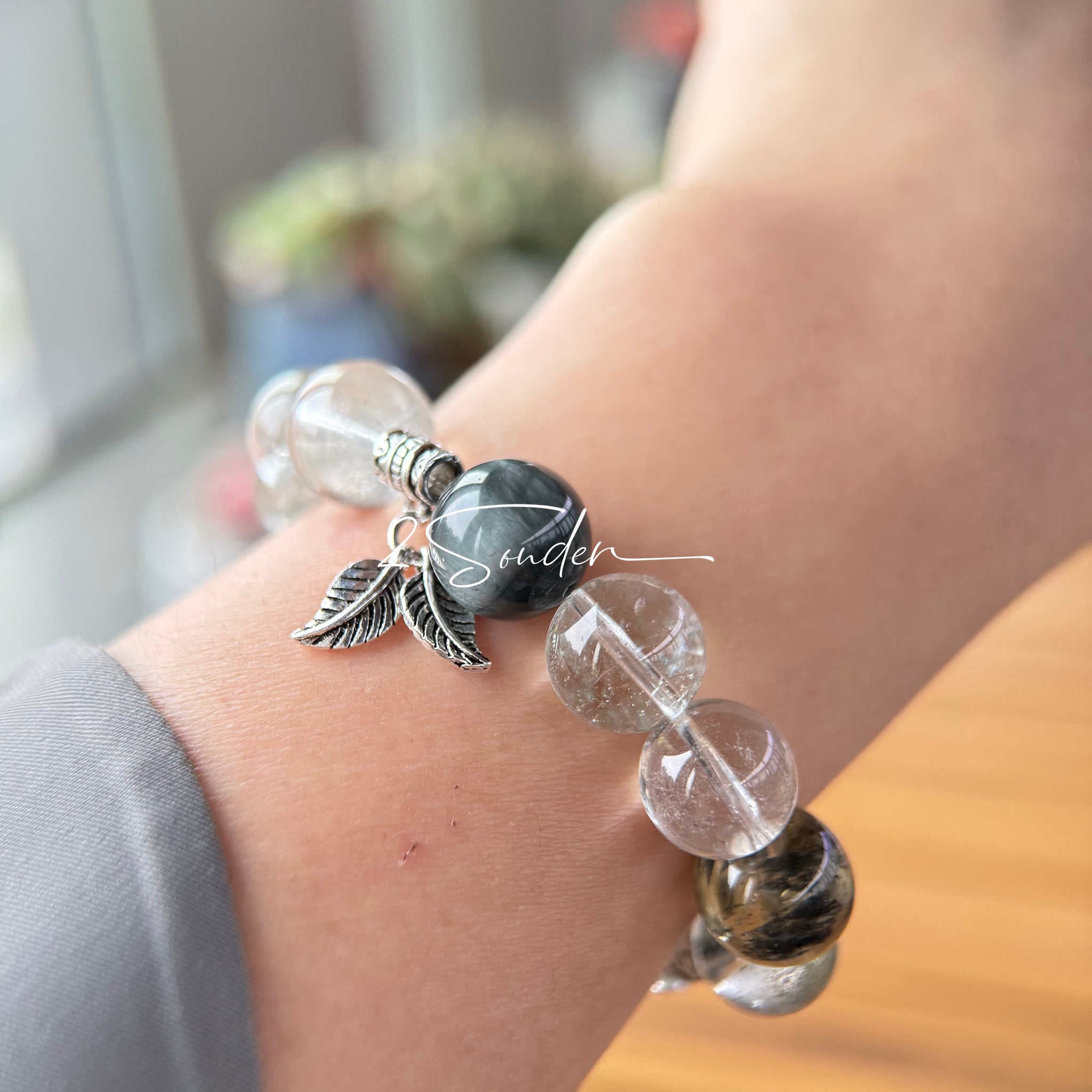 This beaded bracelet is crafted from a mesmerizing combination of Green Phantom Quartz, Blue Rabbit Hair Quartz, Hawk's Eye, Black Aurora Super Seven, and Herkimer. All the beads are natural crystals. The natural patterns of the crystals intertwine beautifully with the metallic accents, creating a unique and enchanting piece.