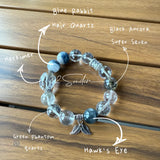 This beaded bracelet is crafted from a mesmerizing combination of Green Phantom Quartz, Blue Rabbit Hair Quartz, Hawk's Eye, Black Aurora Super Seven, and Herkimer. All the beads are natural crystals. The natural patterns of the crystals intertwine beautifully with the metallic accents, creating a unique and enchanting piece.