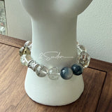 This beaded bracelet is crafted from a mesmerizing combination of Green Phantom Quartz, Blue Rabbit Hair Quartz, Hawk's Eye, Black Aurora Super Seven, and Herkimer. All the beads are natural crystals. The natural patterns of the crystals intertwine beautifully with the metallic accents, creating a unique and enchanting piece.
