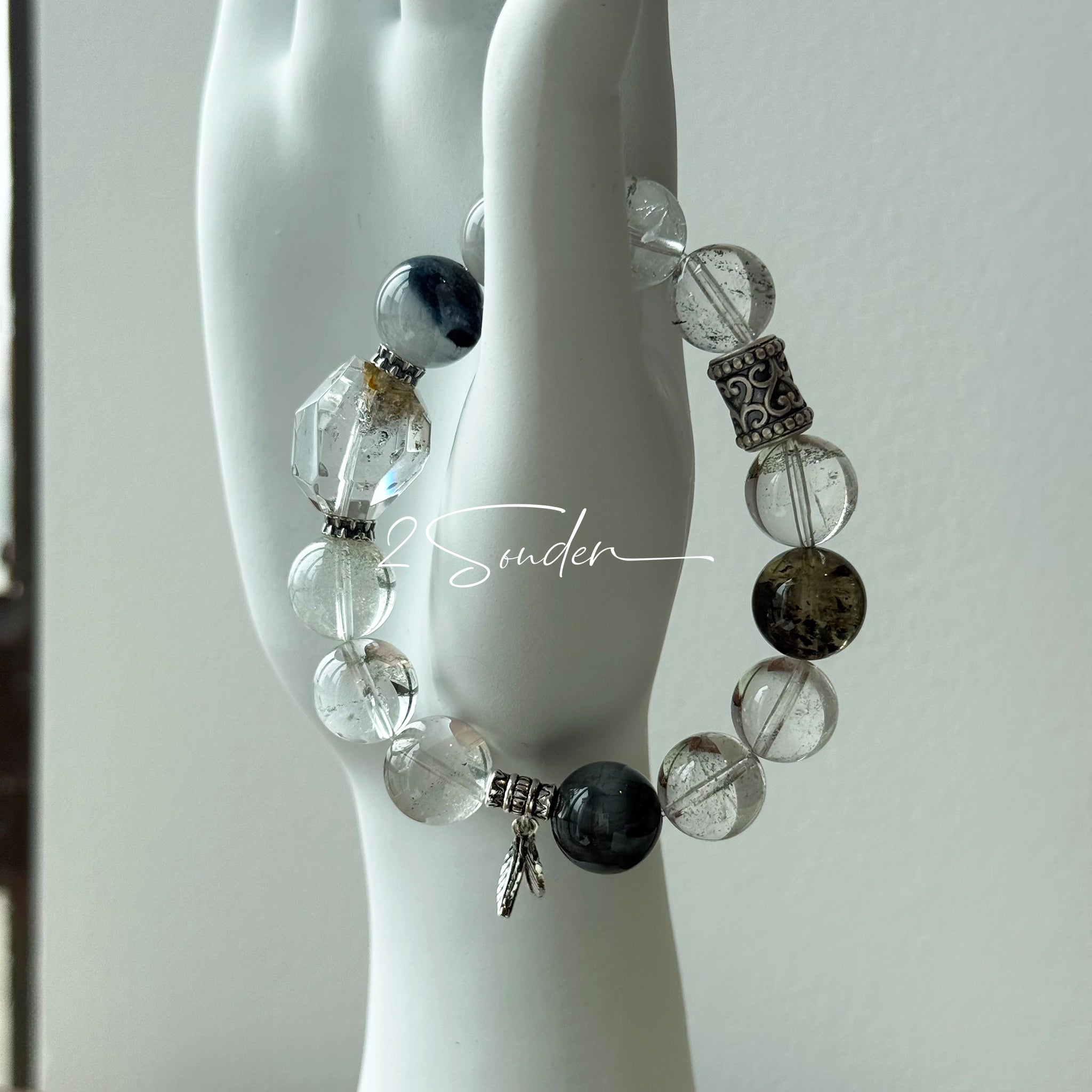 This beaded bracelet is crafted from a mesmerizing combination of Green Phantom Quartz, Blue Rabbit Hair Quartz, Hawk's Eye, Black Aurora Super Seven, and Herkimer. All the beads are natural crystals. The natural patterns of the crystals intertwine beautifully with the metallic accents, creating a unique and enchanting piece.
