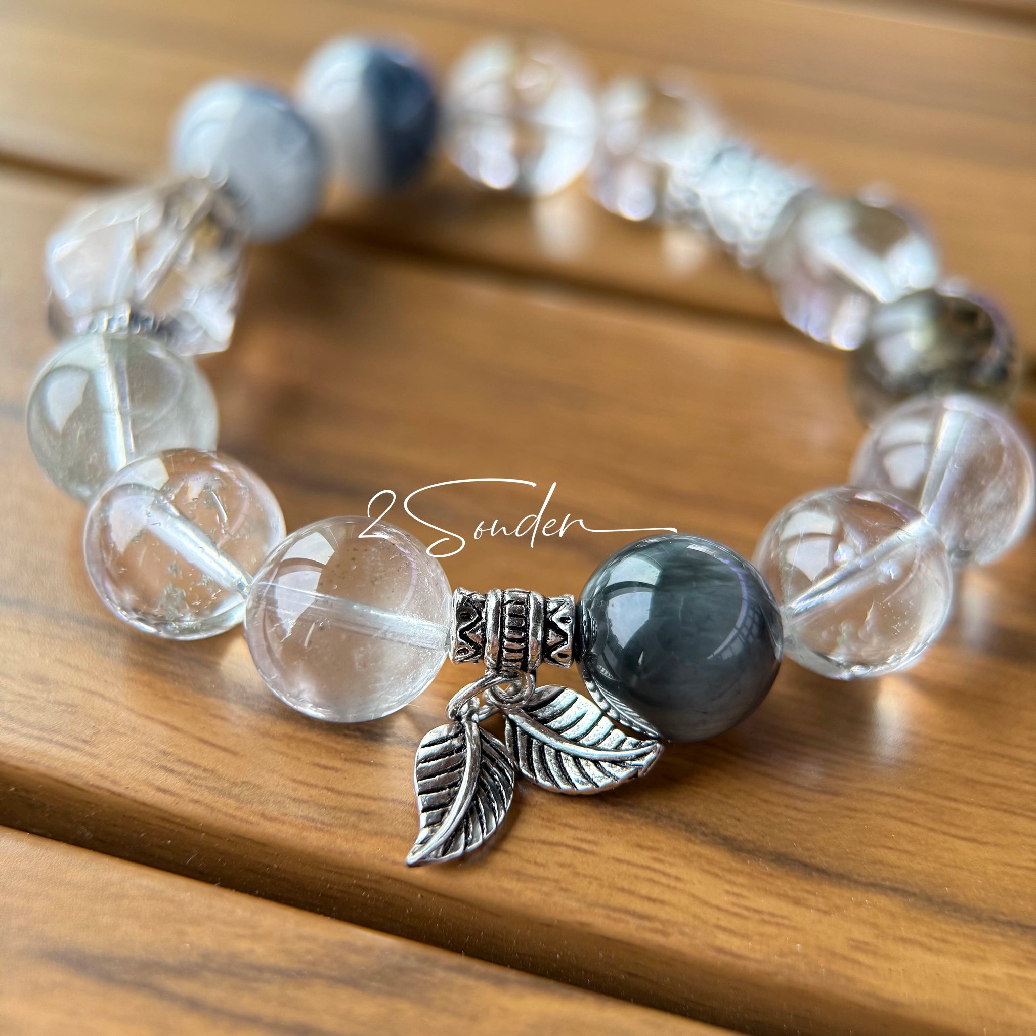 This beaded bracelet is crafted from a mesmerizing combination of Green Phantom Quartz, Blue Rabbit Hair Quartz, Hawk's Eye, Black Aurora Super Seven, and Herkimer. All the beads are natural crystals. The natural patterns of the crystals intertwine beautifully with the metallic accents, creating a unique and enchanting piece.