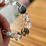 This beaded bracelet is crafted from a mesmerizing combination of Green Phantom Quartz, Blue Rabbit Hair Quartz, Hawk's Eye, Black Aurora Super Seven, and Herkimer. All the beads are natural crystals. The natural patterns of the crystals intertwine beautifully with the metallic accents, creating a unique and enchanting piece.