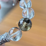 This beaded bracelet is crafted from a mesmerizing combination of Green Phantom Quartz, Blue Rabbit Hair Quartz, Hawk's Eye, Black Aurora Super Seven, and Herkimer. All the beads are natural crystals. The natural patterns of the crystals intertwine beautifully with the metallic accents, creating a unique and enchanting piece.
