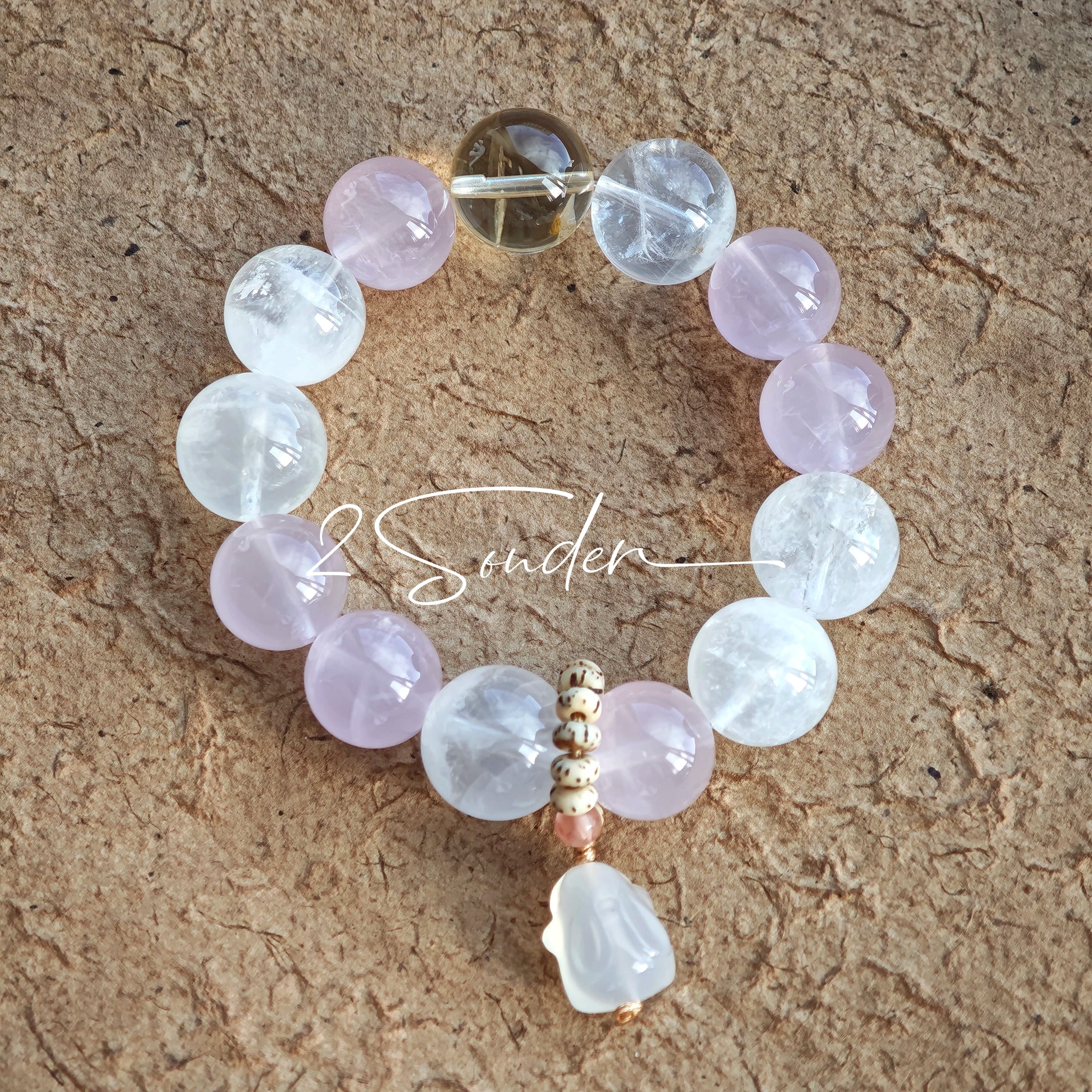 This natural crystal bracelet features a serene mix of white phantom quartz, soft rose quartz, and luminous citrine beads, creating a light, airy aesthetic. Adorned with delicate star-and-moon bodhi seed accents and a milky white chalcedony pendant, it adds a touch of gentle elegance to everyday wear.