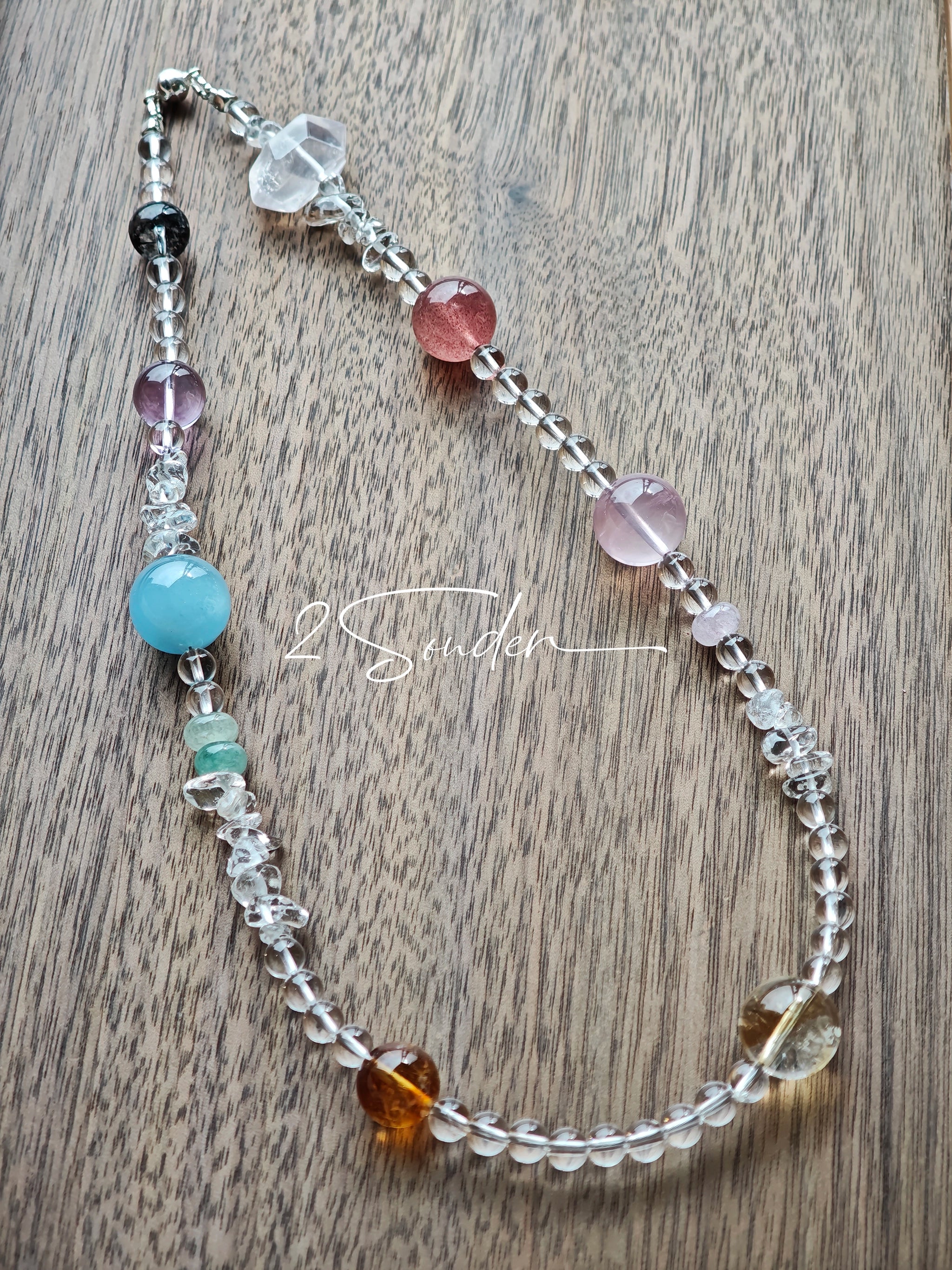 This handcrafted gemstone necklace is a stunning blend of natural crystals, featuring sparkling Herkimer Diamonds, vibrant Brazilian Amethyst, rich Pigeon's Blood Strawberry Quartz, serene Aquamarine, sunny Citrine, and luminous clear quartz, each bead hand-selected for its one-of-a-kind beauty. Strung alongside polished clear quartz spacers and accent stones, the necklace balances bold, colorful statement beads with delicate, shimmering crystal details, creating a piece that feels both earthy and ethereal.