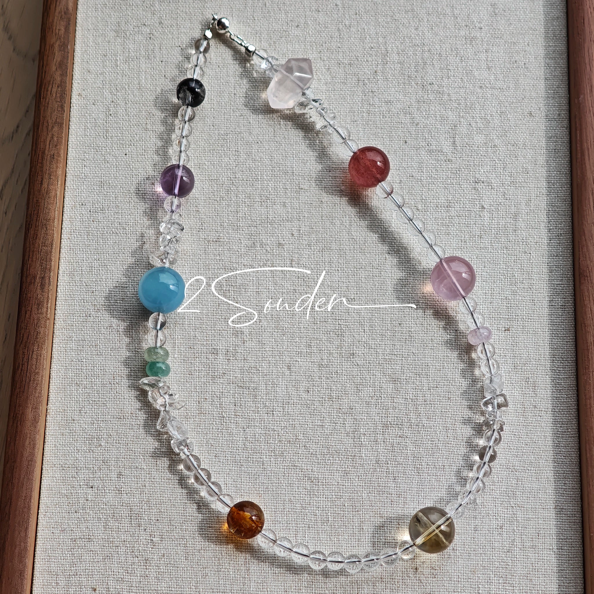 This handcrafted gemstone necklace is a stunning blend of natural crystals, featuring sparkling Herkimer Diamonds, vibrant Brazilian Amethyst, rich Pigeon's Blood Strawberry Quartz, serene Aquamarine, sunny Citrine, and luminous clear quartz, each bead hand-selected for its one-of-a-kind beauty. Strung alongside polished clear quartz spacers and accent stones, the necklace balances bold, colorful statement beads with delicate, shimmering crystal details, creating a piece that feels both earthy and ethereal.