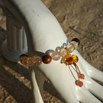 Copper galaxies glitter inside each bead, agarwood whispers mantras, and the floral calabash locks luck in its curl.
