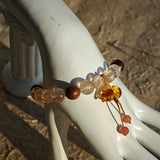 Copper galaxies glitter inside each bead, agarwood whispers mantras, and the floral calabash locks luck in its curl.