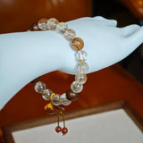 Golden-red needles flash against dark wood grain, while a carved amber gourd blossoms like a lucky lotus at the clasp.