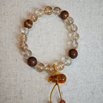 This crystal bracelet unites copper-rutilated quartz with aromatic agarwood beads, finished by a Nanhong-carved flower-amber gourd that symbolizes prosperity and protection.