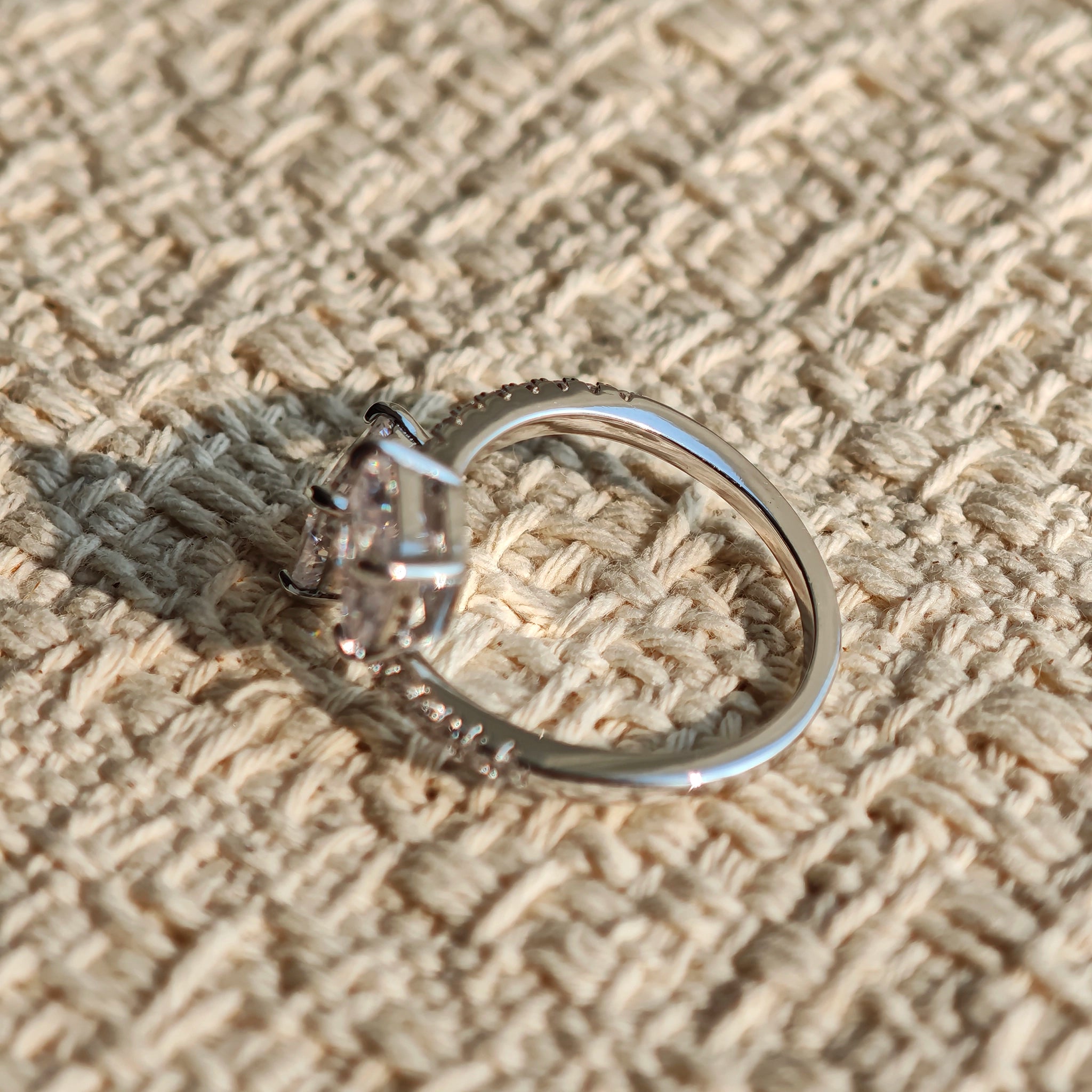 This striking bypass ring showcases two large, brilliant cushion-cut clear stones held securely in classic four-prong settings. The elegant twisted band is lined with a row of sparkling accent Cubic Zirconia stones, delivering a high-end, light luxury aesthetic that instantly catches the eye.