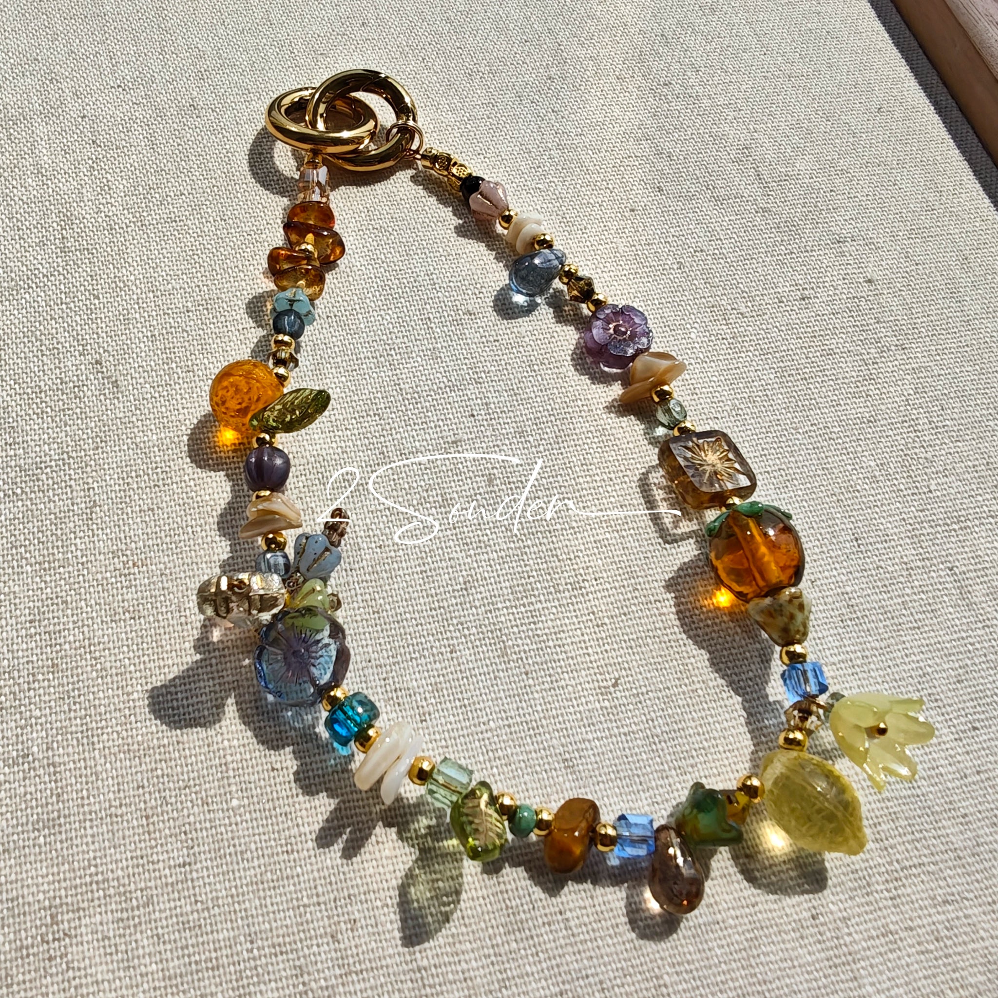 This is a bag charm that made of Czech beads. In the phone strap, there are different spacers like orange, leaves, flowers and lemon. It's with multi colors. This bag charm can also be used as a phone strap and key chain.