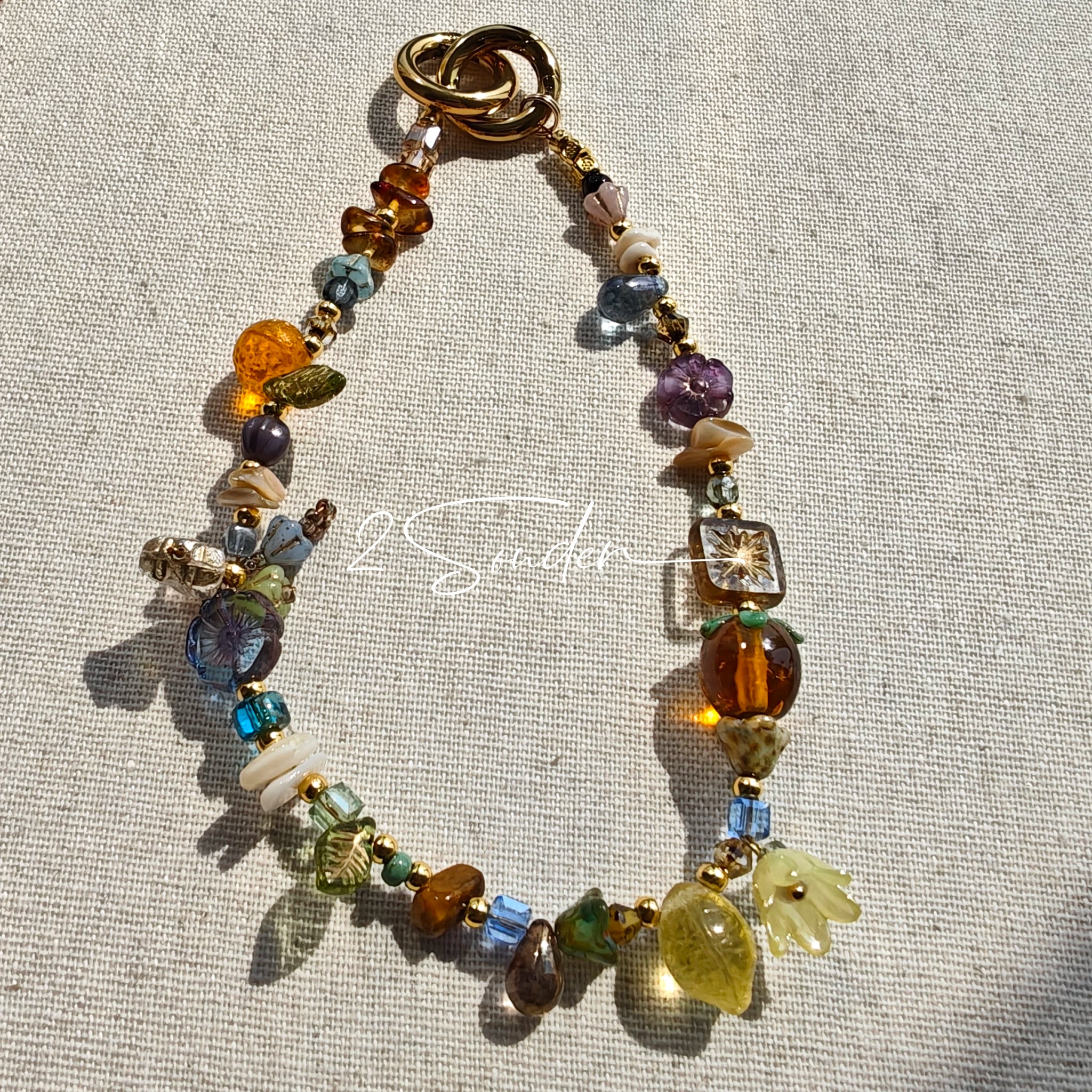 This is a bag charm that made of Czech beads. In the phone strap, there are different spacers like orange, leaves, flowers and lemon. It's with multi colors. This bag charm can also be used as a phone strap and key chain.