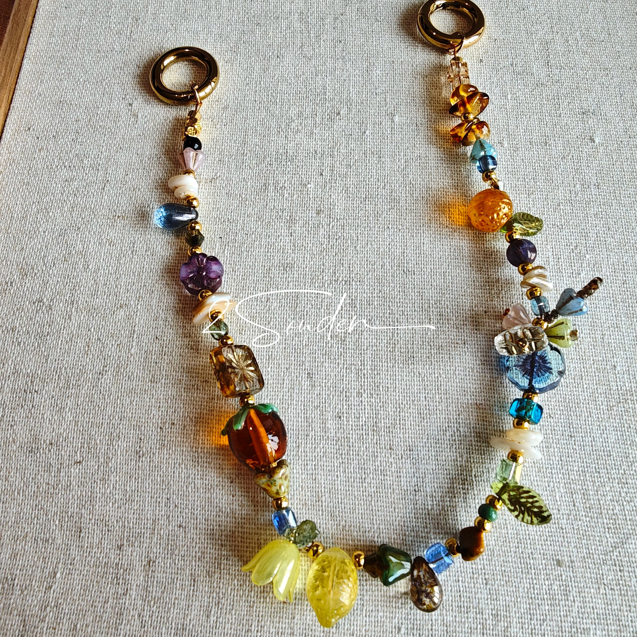 This is a bag charm that made of Czech beads. In the phone strap, there are different spacers like orange, leaves, flowers and lemon. It's with multi colors. This bag charm can also be used as a phone strap and key chain.