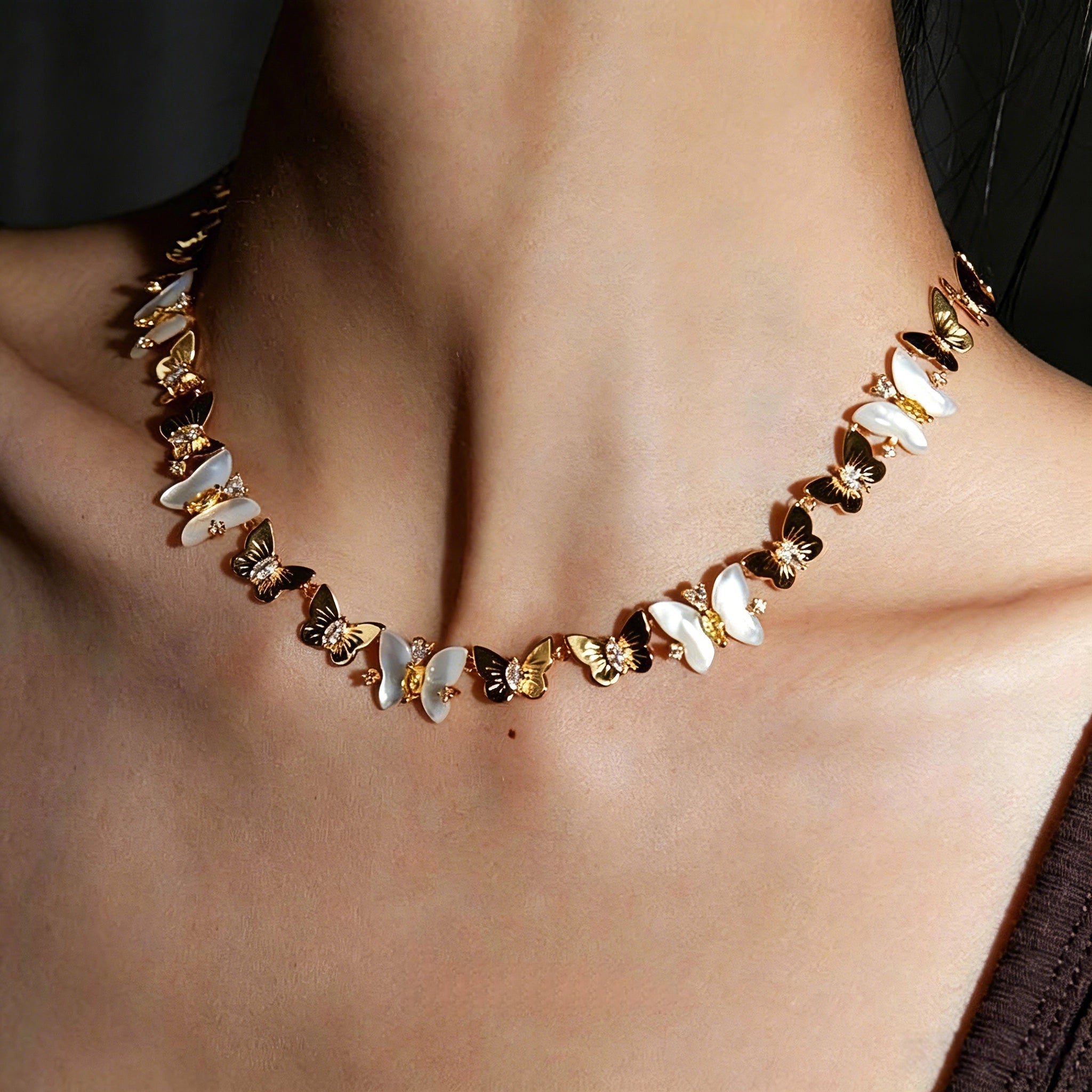 This delicate choker necklace features alternating polished metal butterflies and lustrous white mother-of-pearl butterflies, accented with tiny sparkling crystals. The shimmering white shell inlays contrast beautifully with the warm gold (or cool silver) metal finish, creating an elegant, whimsical design that sits close to the collarbone.