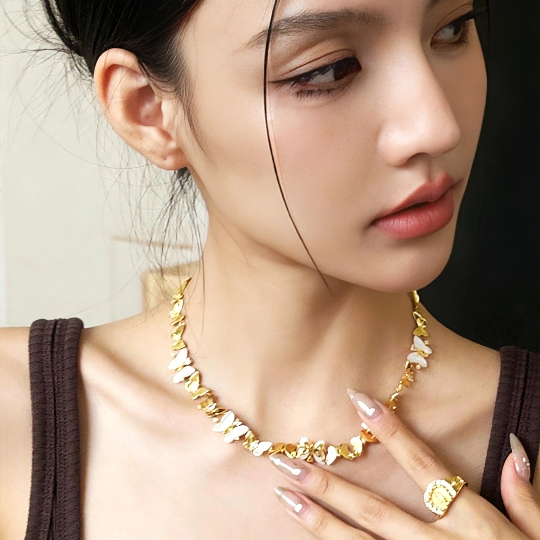 This delicate choker necklace features alternating polished metal butterflies and lustrous white mother-of-pearl butterflies, accented with tiny sparkling crystals. The shimmering white shell inlays contrast beautifully with the warm gold (or cool silver) metal finish, creating an elegant, whimsical design that sits close to the collarbone.