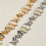 This delicate choker necklace features alternating polished metal butterflies and lustrous white mother-of-pearl butterflies, accented with tiny sparkling crystals. The shimmering white shell inlays contrast beautifully with the warm gold (or cool silver) metal finish, creating an elegant, whimsical design that sits close to the collarbone.