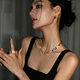 This delicate choker necklace features alternating polished metal butterflies and lustrous white mother-of-pearl butterflies, accented with tiny sparkling crystals. The shimmering white shell inlays contrast beautifully with the warm gold (or cool silver) metal finish, creating an elegant, whimsical design that sits close to the collarbone.