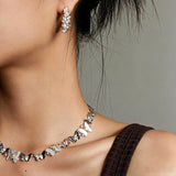 This delicate choker necklace features alternating polished metal butterflies and lustrous white mother-of-pearl butterflies, accented with tiny sparkling crystals. The shimmering white shell inlays contrast beautifully with the warm gold (or cool silver) metal finish, creating an elegant, whimsical design that sits close to the collarbone.