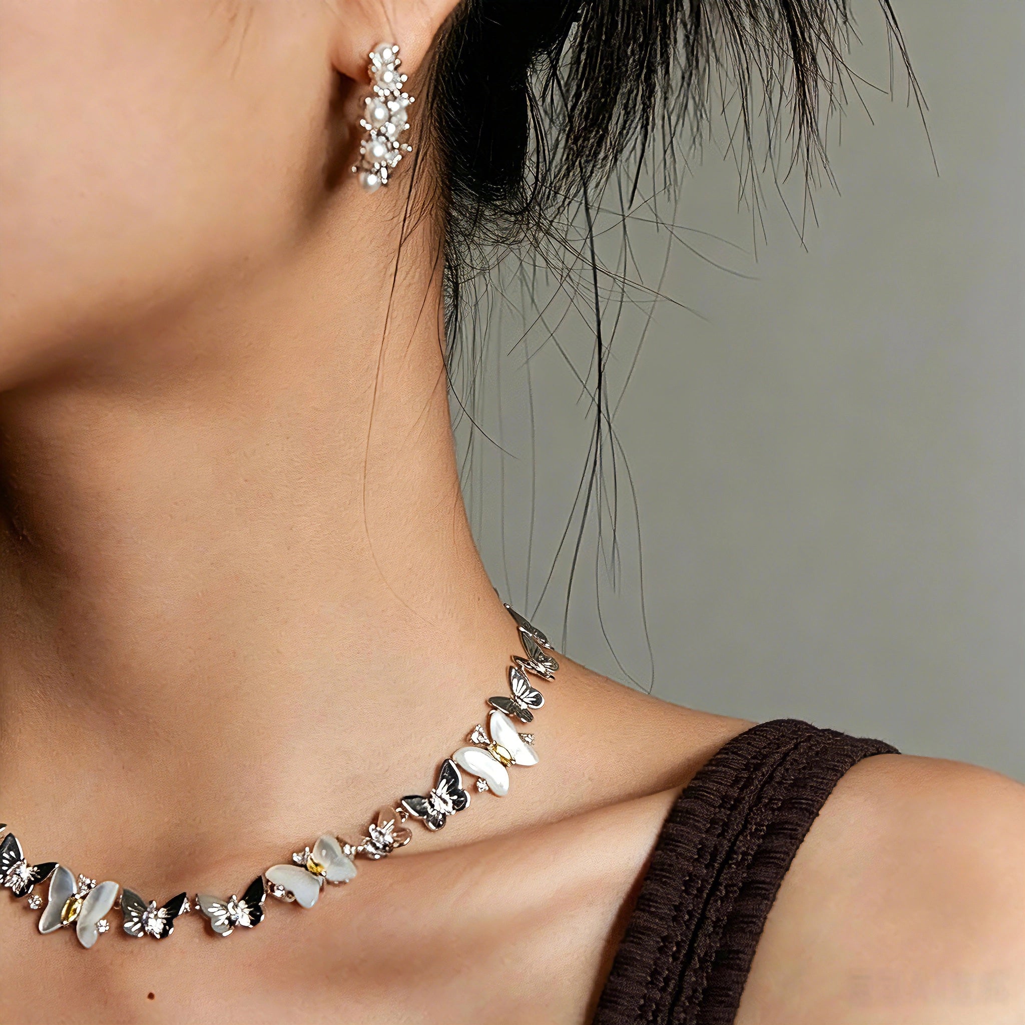 This delicate choker necklace features alternating polished metal butterflies and lustrous white mother-of-pearl butterflies, accented with tiny sparkling crystals. The shimmering white shell inlays contrast beautifully with the warm gold (or cool silver) metal finish, creating an elegant, whimsical design that sits close to the collarbone.