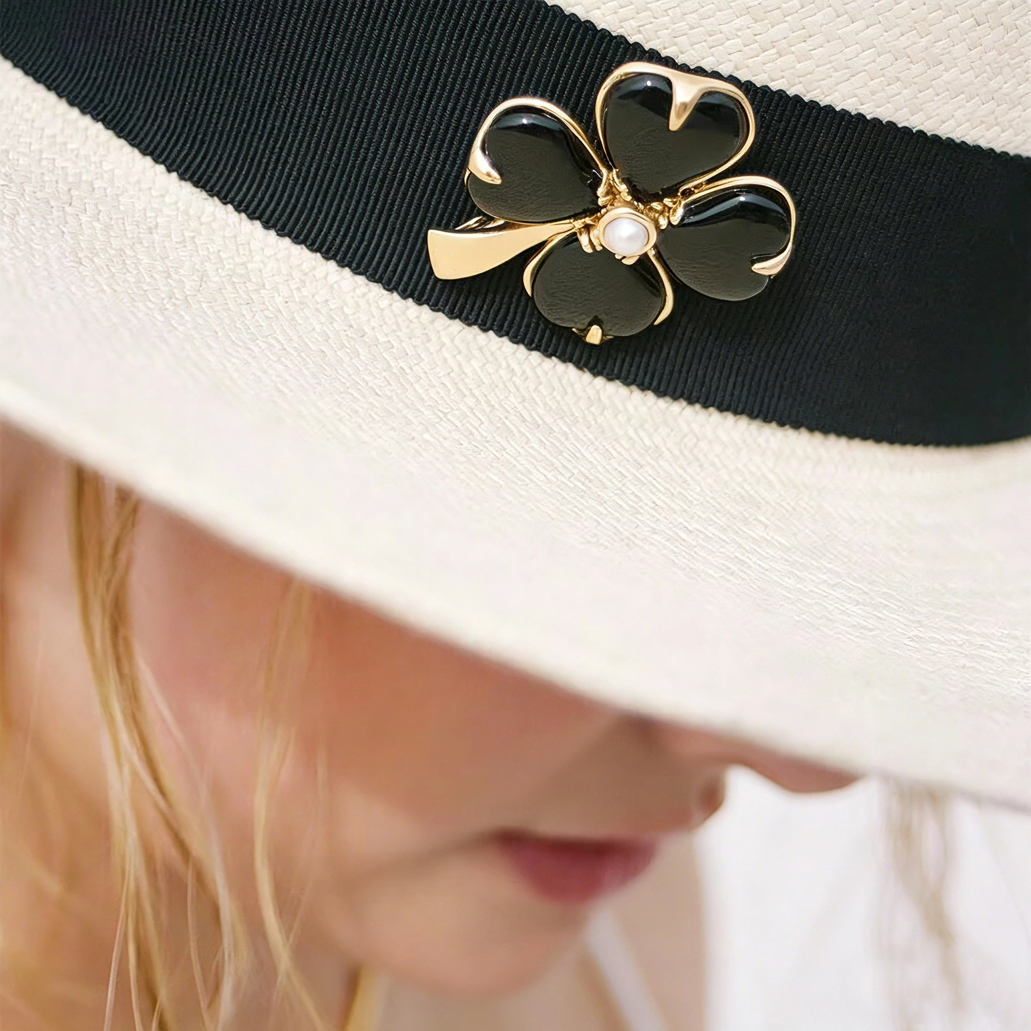 These four-leaf clover brooches come in two elegant versions: one with glossy black onyx petals centered by a delicate pearl, and the other with milky white crystal petals accented by a deep red gemstone at its core. Both are framed in polished gold-toned metal, exuding a classic, vintage-inspired charm.