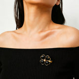These four-leaf clover brooches come in two elegant versions: one with glossy black onyx petals centered by a delicate pearl, and the other with milky white crystal petals accented by a deep red gemstone at its core. Both are framed in polished gold-toned metal, exuding a classic, vintage-inspired charm.