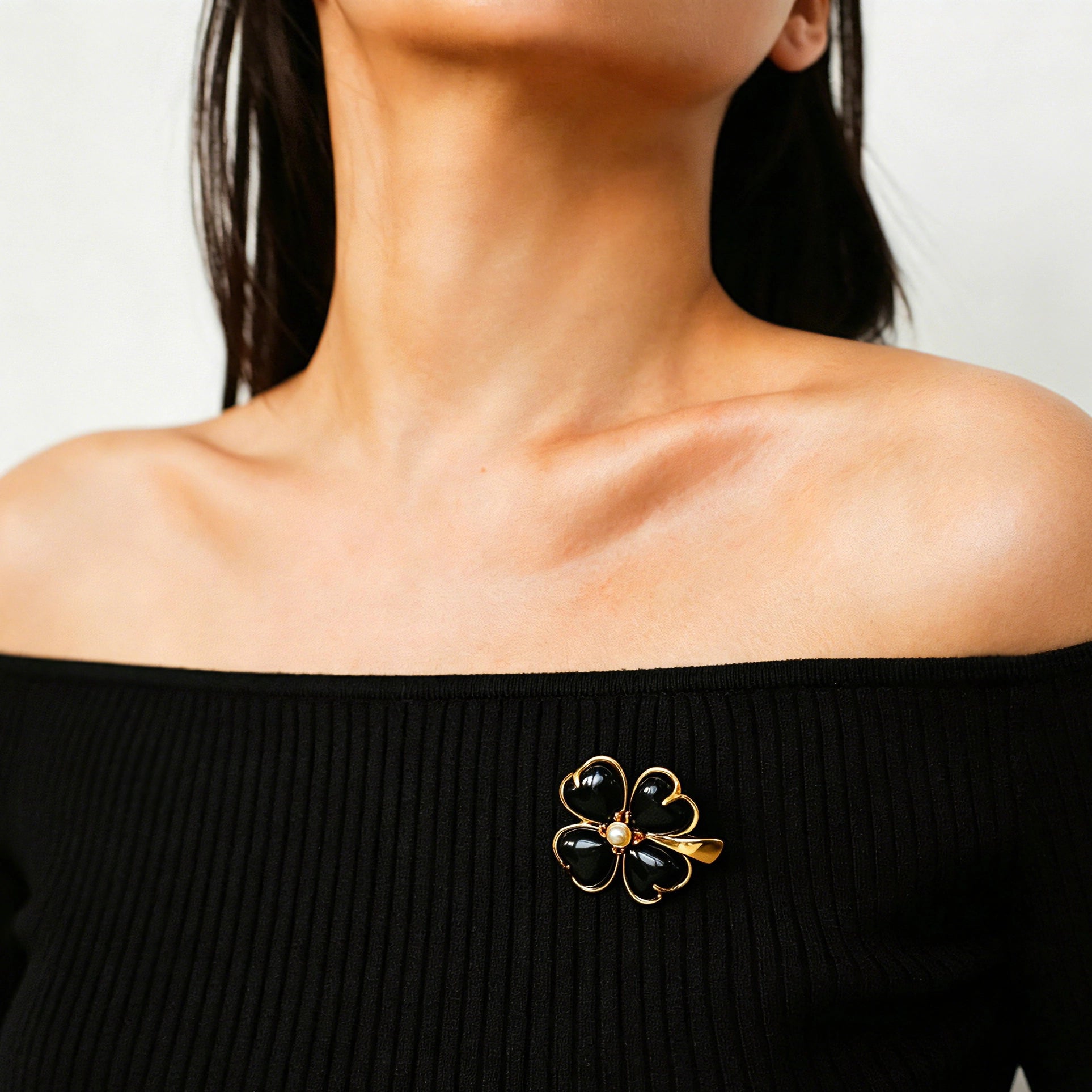 These four-leaf clover brooches come in two elegant versions: one with glossy black onyx petals centered by a delicate pearl, and the other with milky white crystal petals accented by a deep red gemstone at its core. Both are framed in polished gold-toned metal, exuding a classic, vintage-inspired charm.