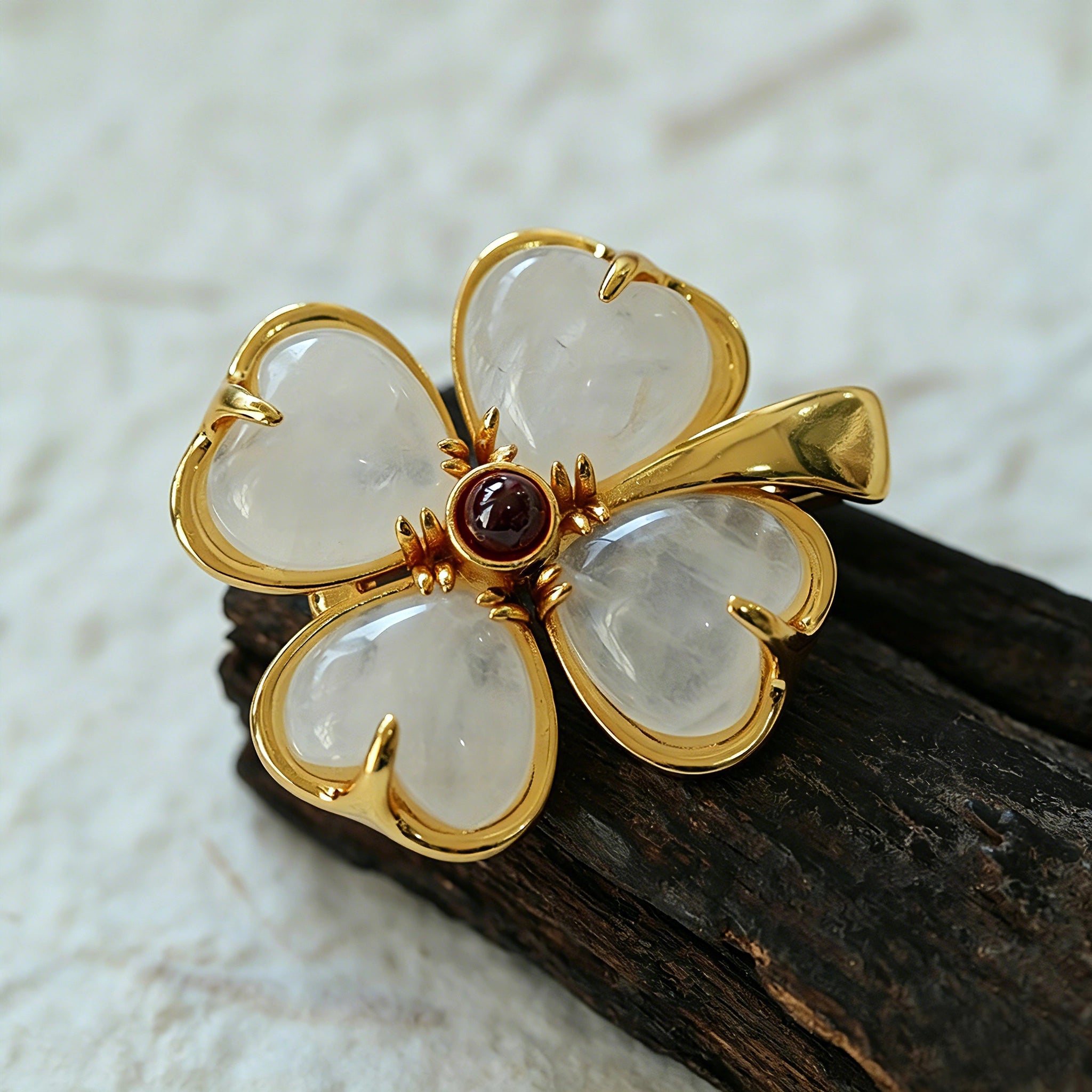 These four-leaf clover brooches come in two elegant versions: one with glossy black onyx petals centered by a delicate pearl, and the other with milky white crystal petals accented by a deep red gemstone at its core. Both are framed in polished gold-toned metal, exuding a classic, vintage-inspired charm.