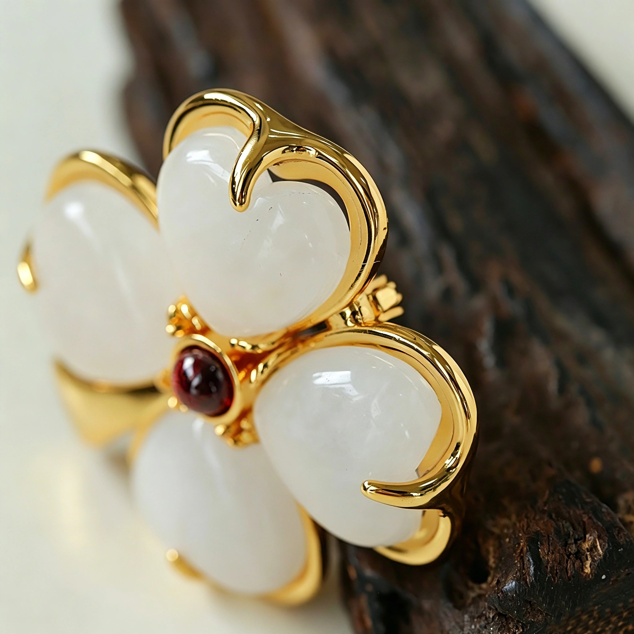 These four-leaf clover brooches come in two elegant versions: one with glossy black onyx petals centered by a delicate pearl, and the other with milky white crystal petals accented by a deep red gemstone at its core. Both are framed in polished gold-toned metal, exuding a classic, vintage-inspired charm.