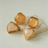 These French vintage-style drop earrings feature a geometric design, crafted with polished gold-tone metal settings. Each earring is adorned with two linked gemstone pendants: a cushion-cut square top and a heart-shaped bottom, made from natural agate in rich, varied hues like warm orange, deep blue, forest green, and vibrant red. The elegant, retro silhouette blends classic charm with a bold, colorful aesthetic, perfect for adding a statement touch to any look.
