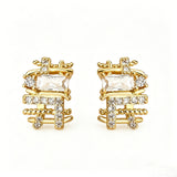 These 18k real gold-plated stud earrings feature an intricate geometric woven design, crafted with twisted gold tones that create a luxurious, textured look. Adorned with a central rectangular baguette-cut zirconia stone surrounded by round pavé-set zircons, they sparkle brilliantly with a blend of clear cubic zirconia and golden metalwork. The elegant yet bold silhouette combines modern geometry with timeless glamour, making it a striking accessory.