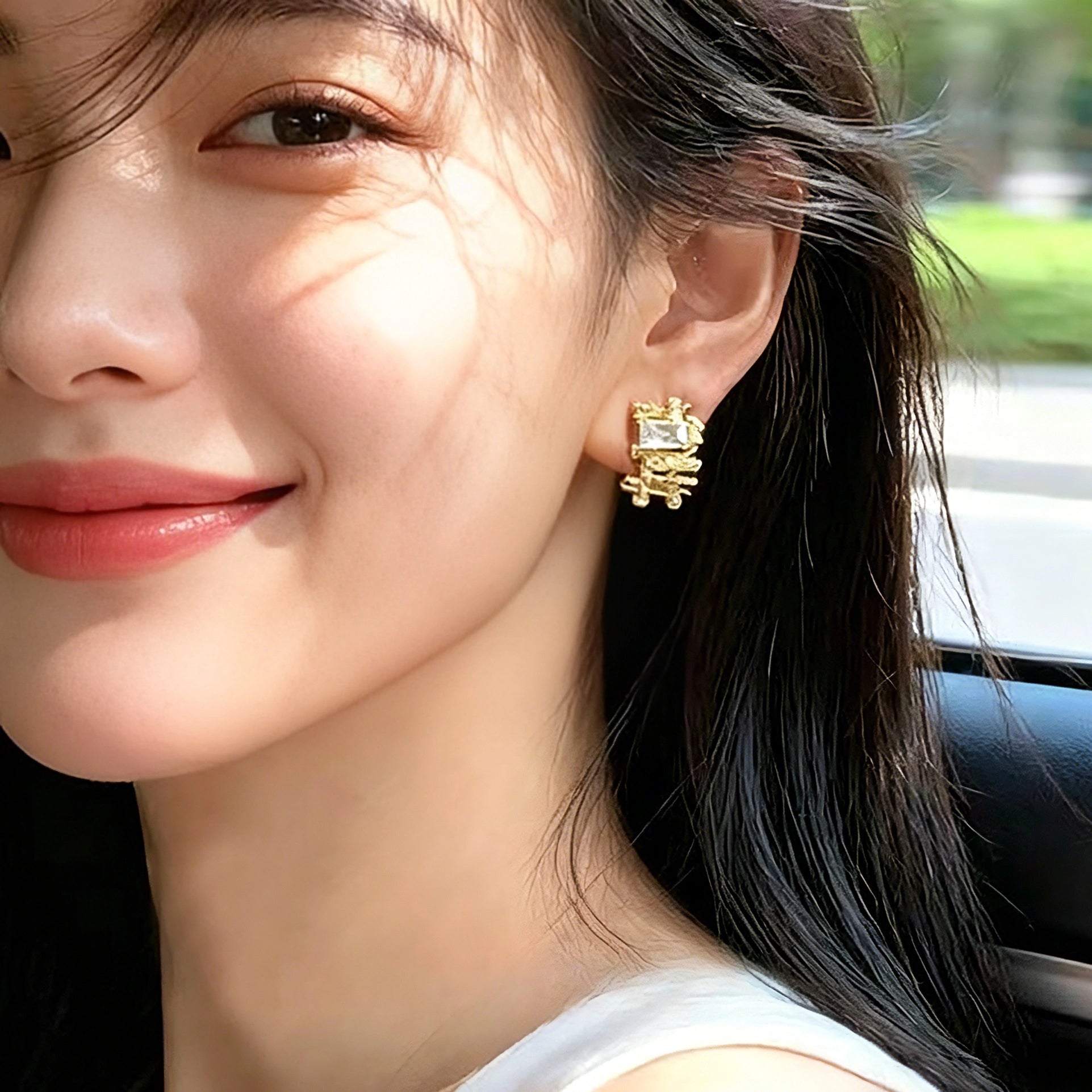 These 18k real gold-plated stud earrings feature an intricate geometric woven design, crafted with twisted gold tones that create a luxurious, textured look. Adorned with a central rectangular baguette-cut zirconia stone surrounded by round pavé-set zircons, they sparkle brilliantly with a blend of clear cubic zirconia and golden metalwork. The elegant yet bold silhouette combines modern geometry with timeless glamour, making it a striking accessory.
