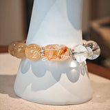 This is a gemstone bracelet made of Golden Hematoid Quartz, Copper Rutilated Quartz, Clear Quartz and Citrine. In the bracelet, there is also a bow pendant as decoration.