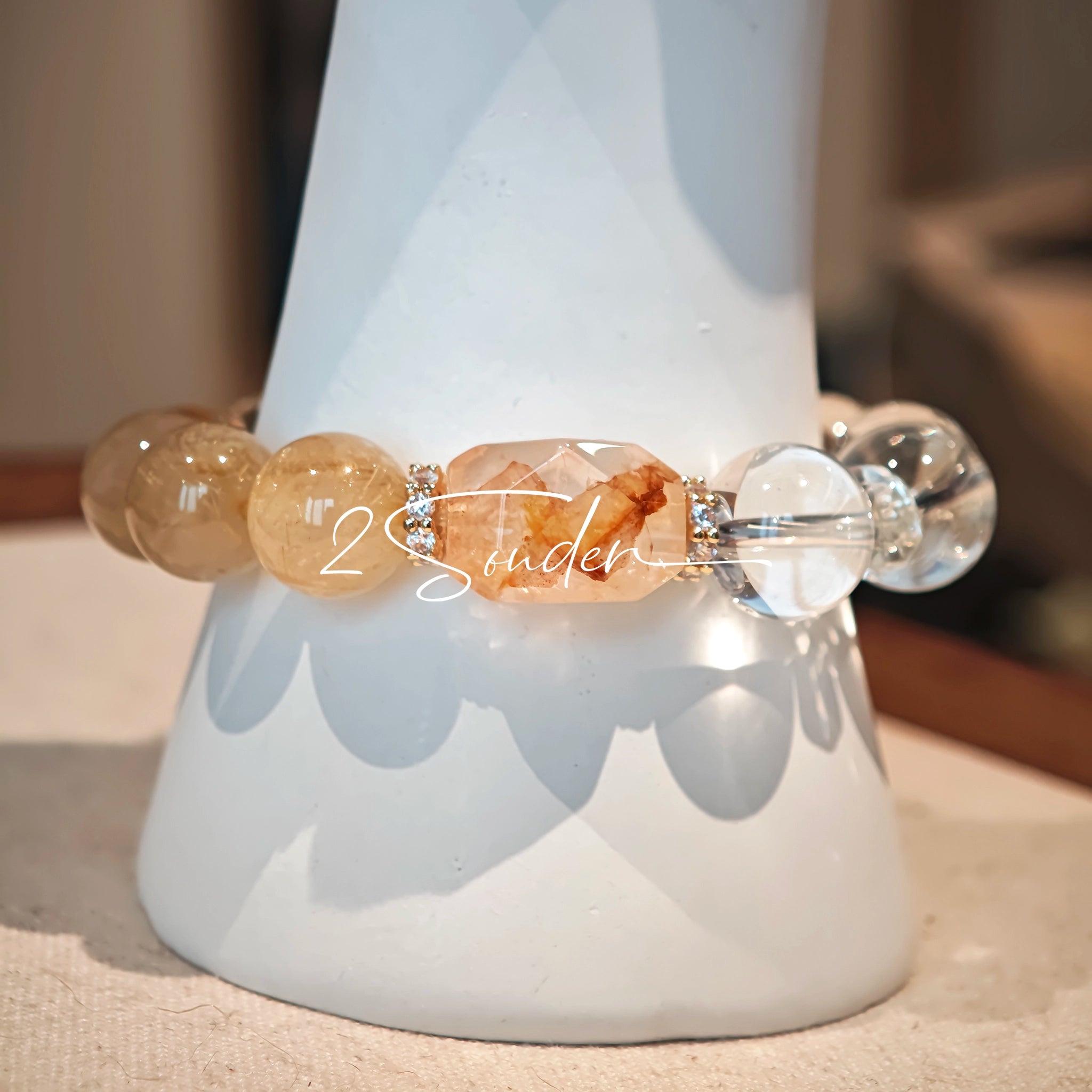 This is a gemstone bracelet made of Golden Hematoid Quartz, Copper Rutilated Quartz, Clear Quartz and Citrine. In the bracelet, there is also a bow pendant as decoration.