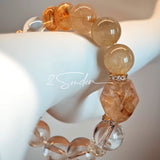 This is a gemstone bracelet made of Golden Hematoid Quartz, Copper Rutilated Quartz, Clear Quartz and Citrine. In the bracelet, there is also a bow pendant as decoration.