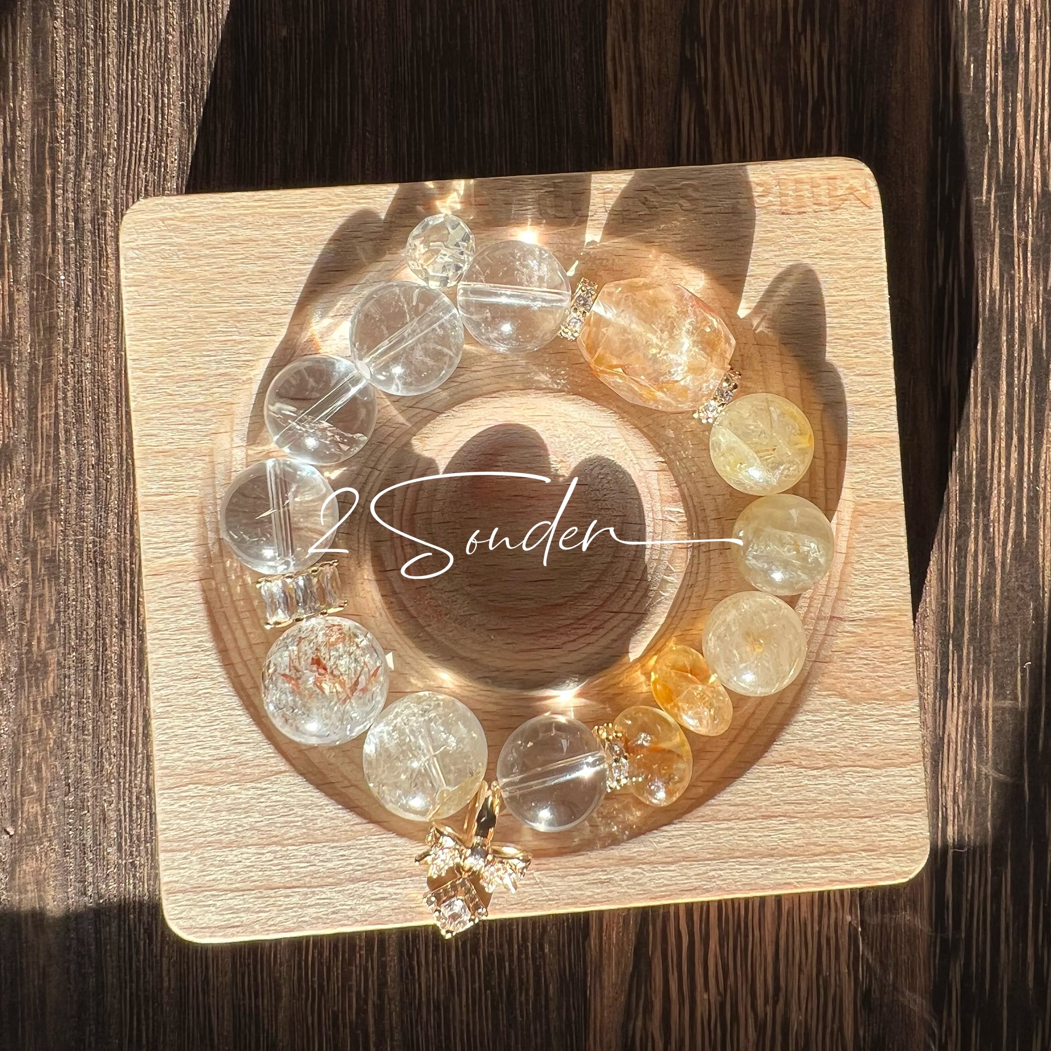 This is a gemstone bracelet made of Golden Hematoid Quartz, Copper Rutilated Quartz, Clear Quartz and Citrine. In the bracelet, there is also a bow pendant as decoration.