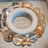 This is a gemstone bracelet made of Golden Hematoid Quartz, Copper Rutilated Quartz, Clear Quartz and Citrine. In the bracelet, there is also a bow pendant as decoration.