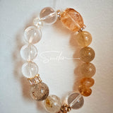 This is a gemstone bracelet made of Golden Hematoid Quartz, Copper Rutilated Quartz, Clear Quartz and Citrine. In the bracelet, there is also a bow pendant as decoration.