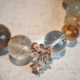This is a gemstone bracelet made of Golden Hematoid Quartz, Copper Rutilated Quartz, Clear Quartz and Citrine. In the bracelet, there is also a bow pendant as decoration.