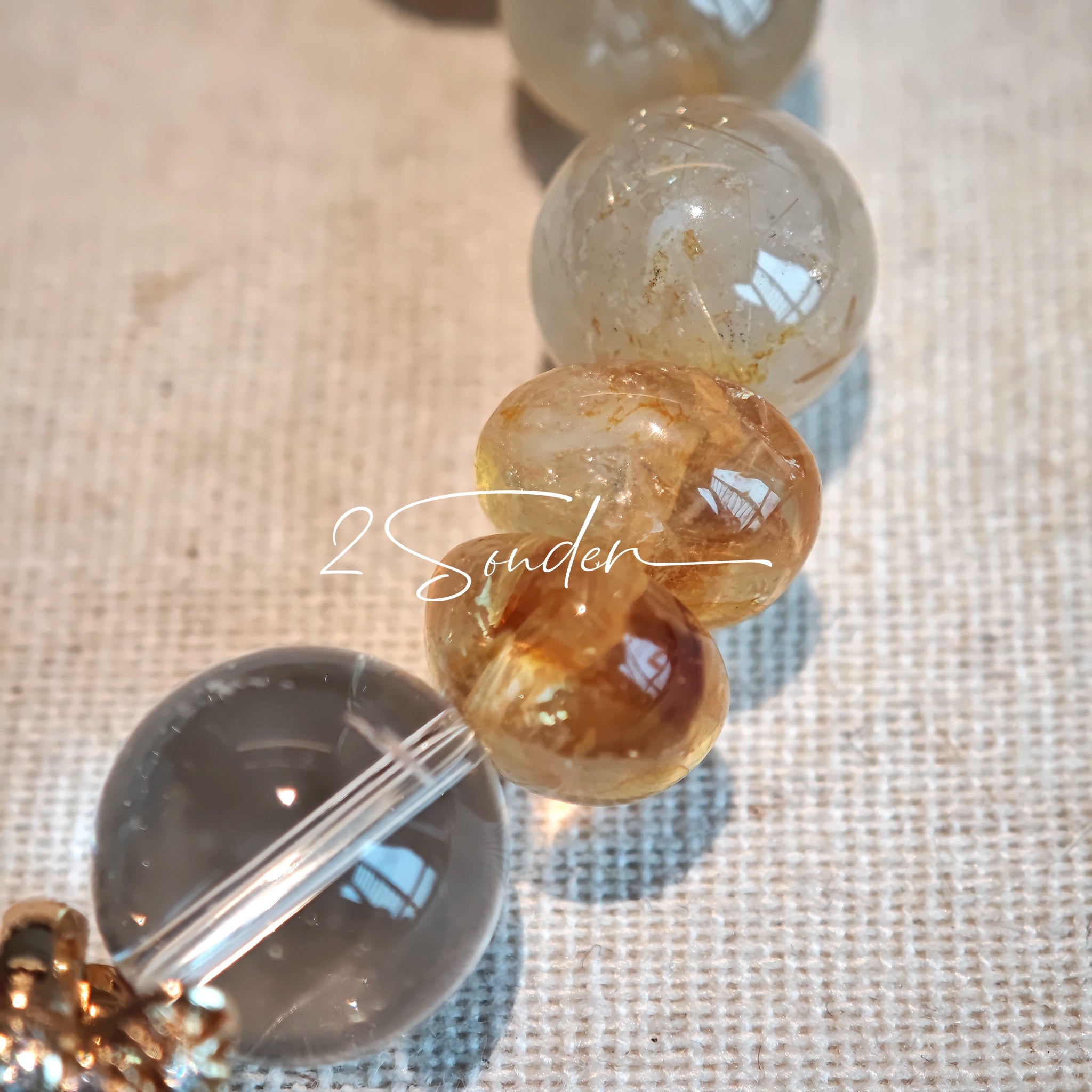 This is a gemstone bracelet made of Golden Hematoid Quartz, Copper Rutilated Quartz, Clear Quartz and Citrine. In the bracelet, there is also a bow pendant as decoration.