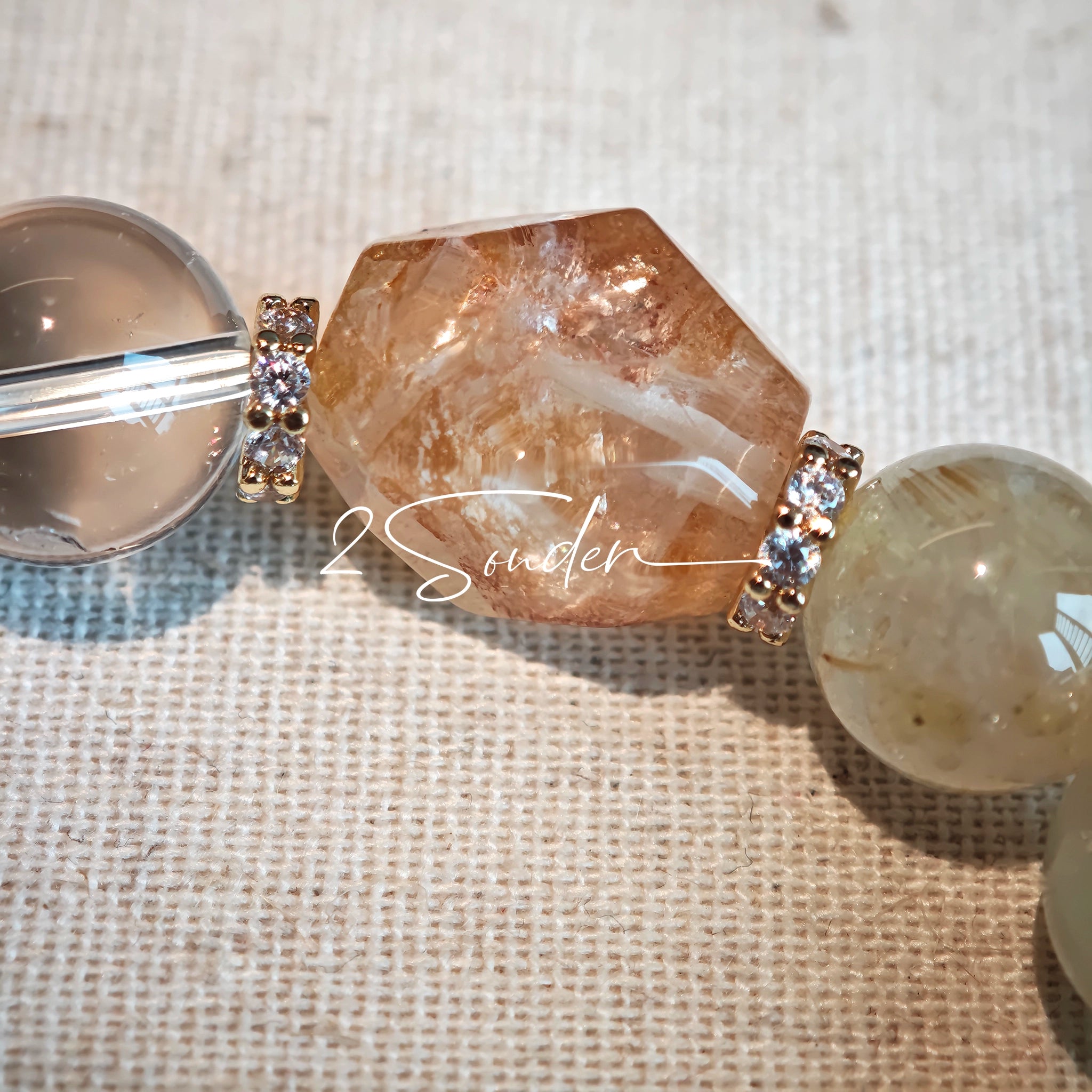 This is a gemstone bracelet made of Golden Hematoid Quartz, Copper Rutilated Quartz, Clear Quartz and Citrine. In the bracelet, there is also a bow pendant as decoration.