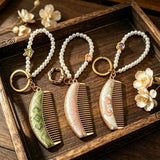  These mini comb keychains are crafted with elegant Chinese Song brocade fabric, showcasing classic traditional patterns in soft green, blush pink, and vintage cream tones. Each delicate hair comb pendant is matched with a glossy pearl lanyard and golden hardware, blending ancient oriental aesthetics with portable daily accessory design. A charming small heritage-style ornament perfect for bags, keys and gifting.