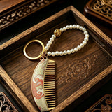  These mini comb keychains are crafted with elegant Chinese Song brocade fabric, showcasing classic traditional patterns in soft green, blush pink, and vintage cream tones. Each delicate hair comb pendant is matched with a glossy pearl lanyard and golden hardware, blending ancient oriental aesthetics with portable daily accessory design. A charming small heritage-style ornament perfect for bags, keys and gifting.
