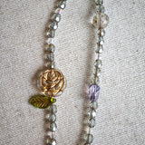 This is a grey czech beads bracelet, decorated with green leaves , bronze and purple flowers, and irregularly shape amber color spacer beads.