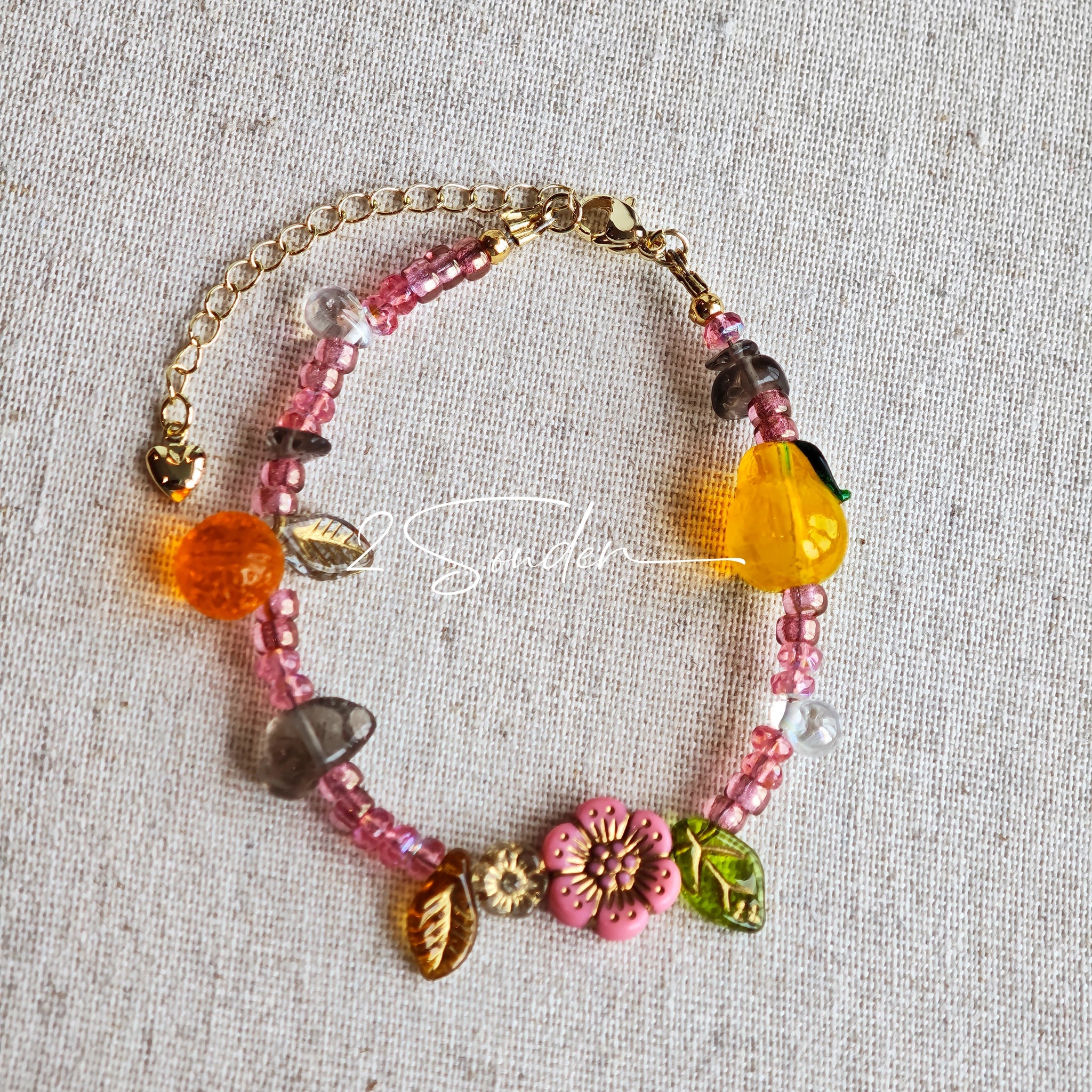 This is a bracelet consist of glass beads. The main color of the bracelet is pink. It's also decorated with orange, yellow pear, grey flower, brown leaves and green leaves spacers.