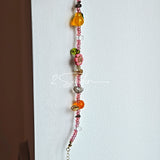 This is a bracelet consist of glass beads. The main color of the bracelet is pink. It's also decorated with orange, yellow pear, grey flower, brown leaves and green leaves spacers.