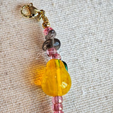 This is a bracelet consist of glass beads. The main color of the bracelet is pink. It's also decorated with orange, yellow pear, grey flower, brown leaves and green leaves spacers.