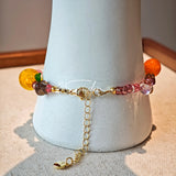 This is a bracelet consist of glass beads. The main color of the bracelet is pink. It's also decorated with orange, yellow pear, grey flower, brown leaves and green leaves spacers.