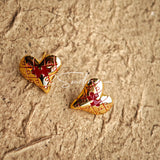 This is a pair of heart earrings with puzzle blocks pattern on the surface. The earrings feature a vibrant enamel center that mimics a beating heart flowing with love. The material of the earrings is sterling silver and enamel, and the color is vintage gold color
